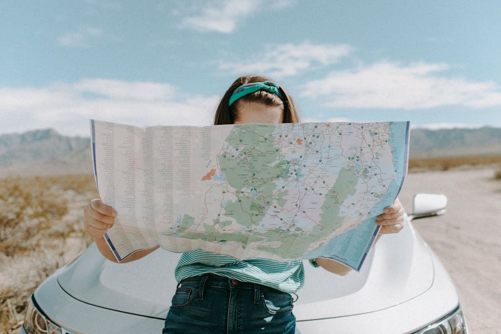 Woman Looking At The Map is identifying when on your roadtrip in remote areas in Australia having technology is great but a basic paper map is essential too