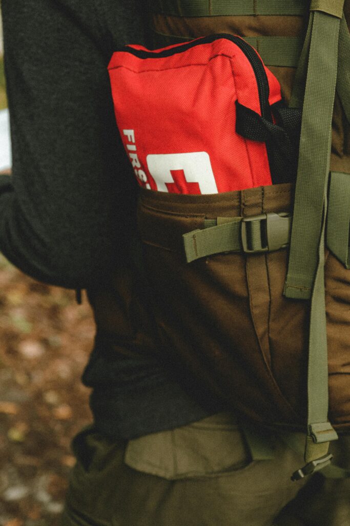 Close-up of a red first aid kit in a hiker's backpack, perfect for outdoor safety.